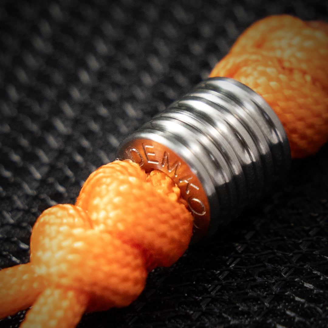 Three precision-machined demko knives titanium beads on an orange parachord lanyard.