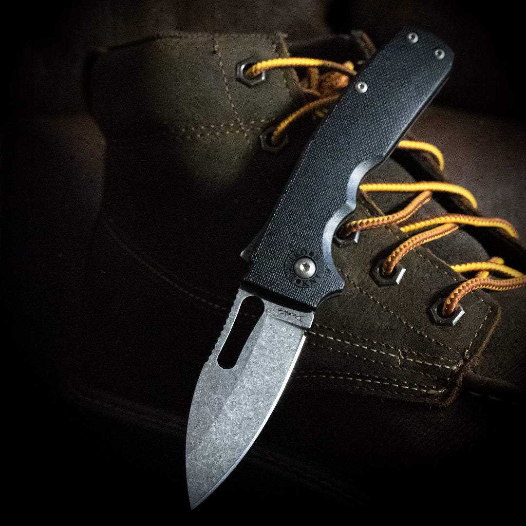 Shark-Cub folding knife open on a wolverine work boot with yellow laces.