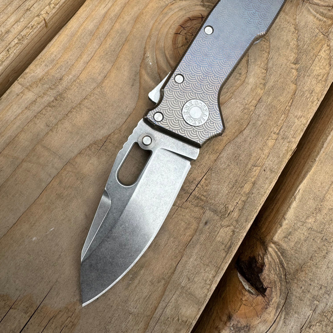 AD20 compact folding knife with anodized titanium laser engraved handle pattern.