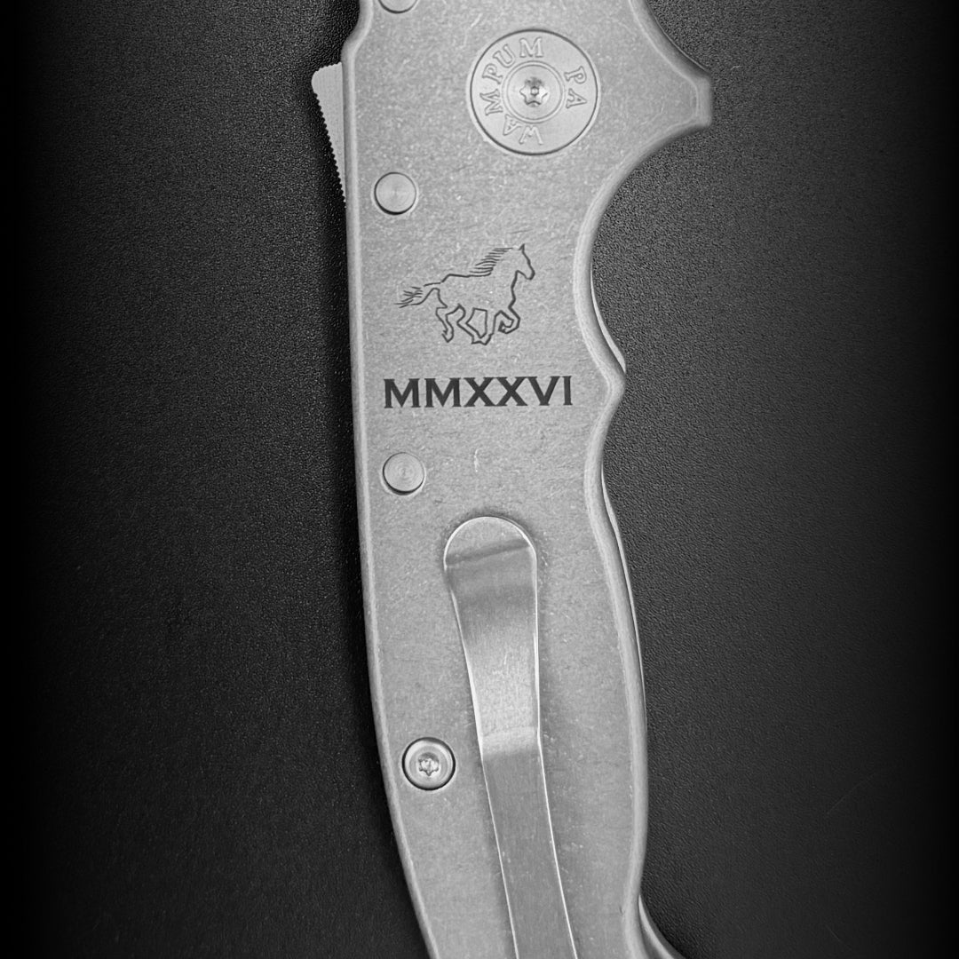 Close-up of the titanium handle scale with a laser etched design showcasing a horse icon and roman numerals.