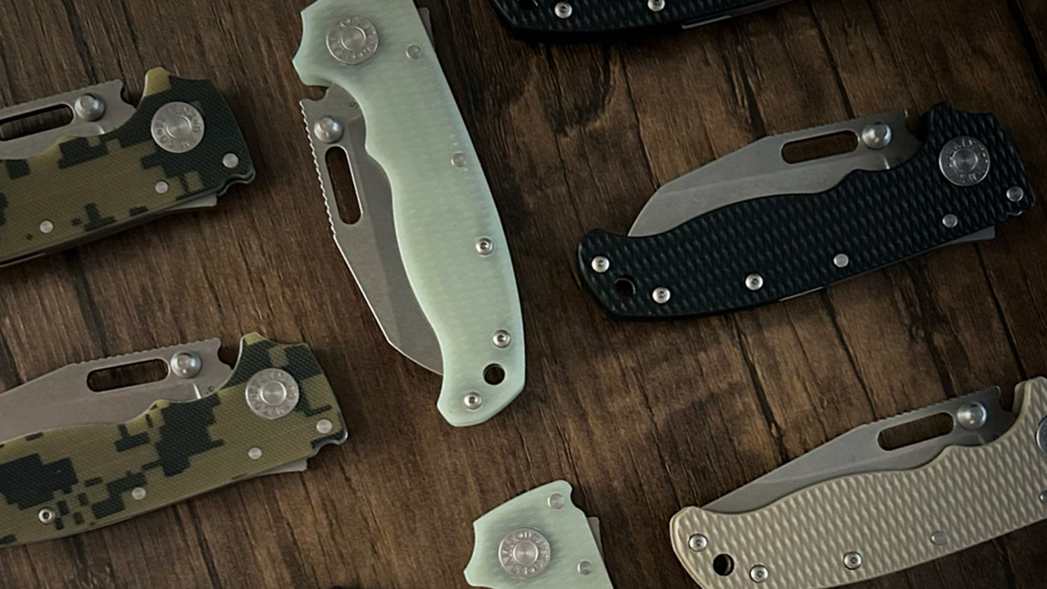 Multiple AD20.5 folding knives on a wooden surface.
