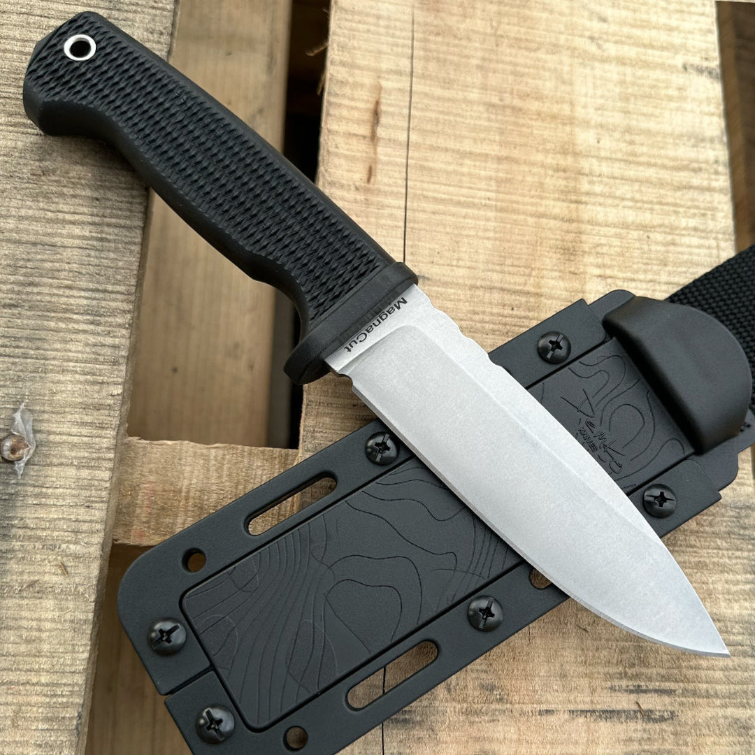 American made FreeReign MagnaCut drop point fixed blade with sheath on a wood background.