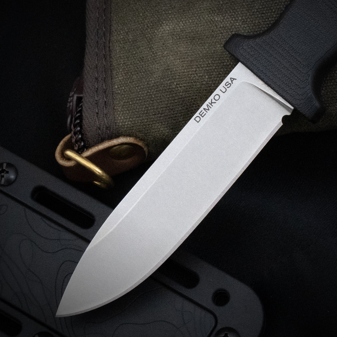 Armiger 4 fixed blade hunting knife with an black handle and sheath laying on a canvas carrying case.