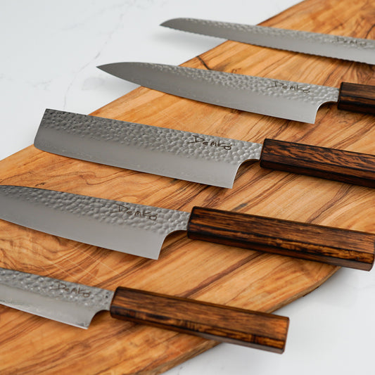 Set of Japanese Kitchen Knives with Japanese Red Oak wooden handles on a wooden cutting board.