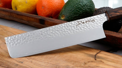 Japanese Nakiri Kitchen Knife with 'Demko' branding on a wooden surface with fruits in the background.