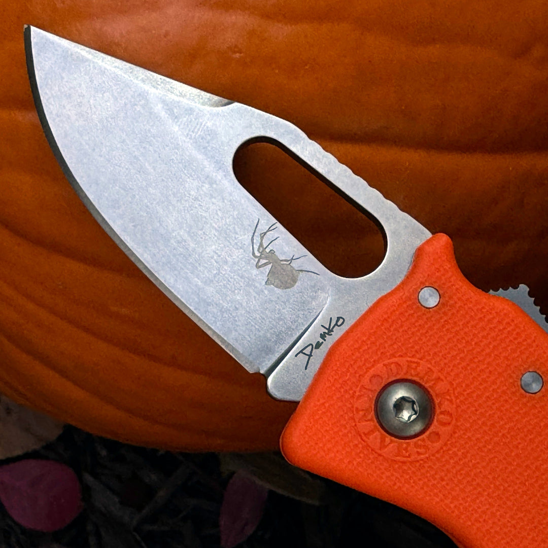 Nano-Shark folding knife with orange handle and halloween themed spider laser etchings.