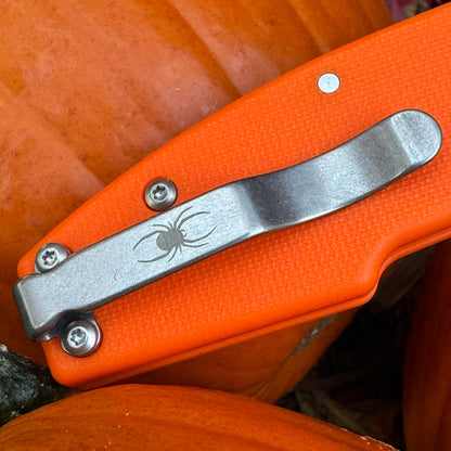 Close-up of pocket clip with a laser etched spider emblem.