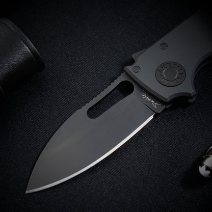 Close up view of the Shark-Cub Stealth with a pen and leather wallet.
